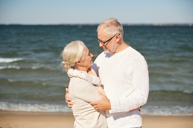 concetto di famiglia, età, viaggi, turismo e persone - coppia senior felice che si abbraccia sulla spiaggia estiva