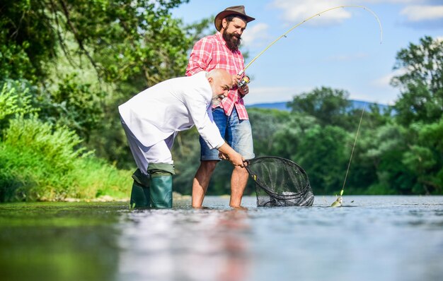 Concetto di famiglia felice Concetto di cattura e pesca Due amici maschi che pescano insieme pesce volante hobby di uomo d'affari pensionamento pesca pescatori felici amicizia papà in pensione e figlio maturo