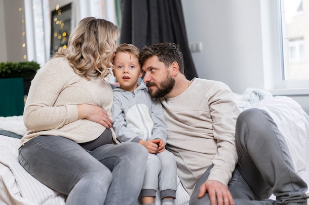 Concetto di famiglia felice Madre, padre e figlio piccolo si divertono a casa Famiglia caucasica al chiuso Papà barba mamma incinta e ragazzino divertente