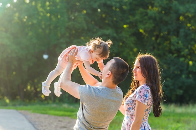 Concetto di famiglia felice - padre, madre e figlia che si divertono e giocano nella natura.