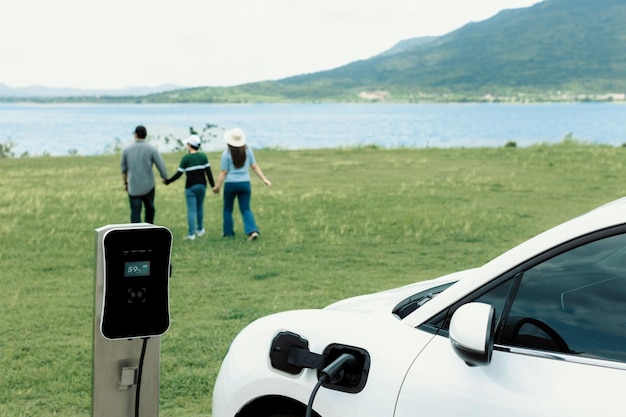 Concetto di famiglia felice progressista al lago di campo verde con veicolo elettrico