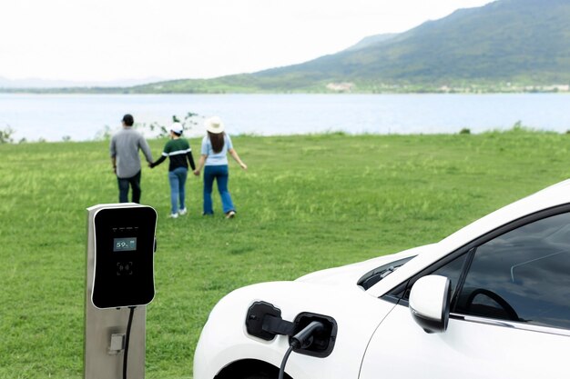 Concetto di famiglia felice progressista al lago di campo verde con veicolo elettrico