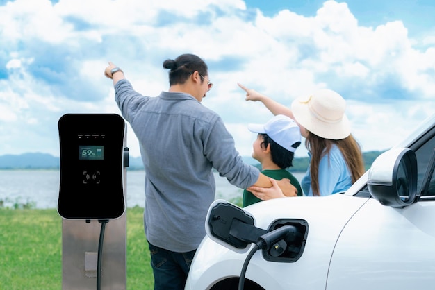 Concetto di famiglia felice progressista con auto EV a scenic naturale all'aperto