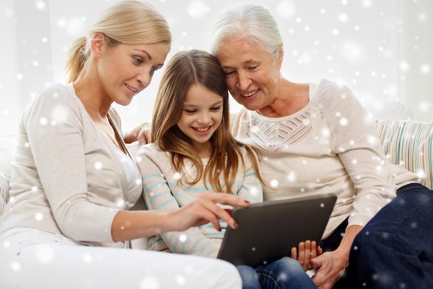 concetto di famiglia, generazione, tecnologia e persone - madre, figlia e nonna sorridenti con computer tablet pc seduto sul divano a casa