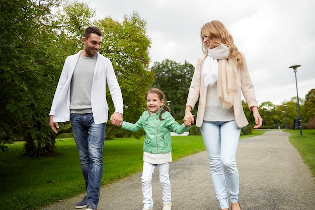 concetto di famiglia, genitorialità, adozione e persone - madre felice, padre e bambina che camminano nel parco estivo