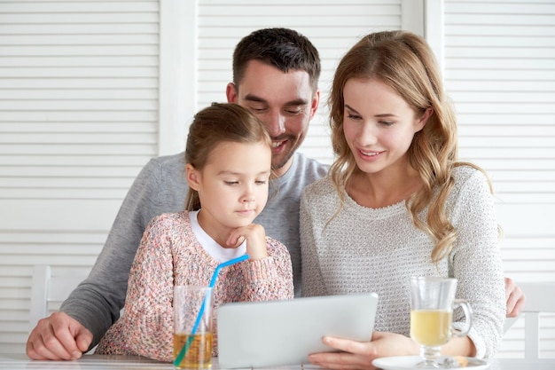 concetto di famiglia, genitorialità, tecnologia e persone - madre felice, padre e bambina con computer tablet pc a cena al ristorante