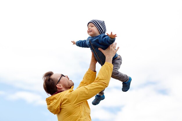 concetto di famiglia, infanzia, paternità, tempo libero e persone - padre felice e figlio piccolo che giocano e si divertono all'aperto