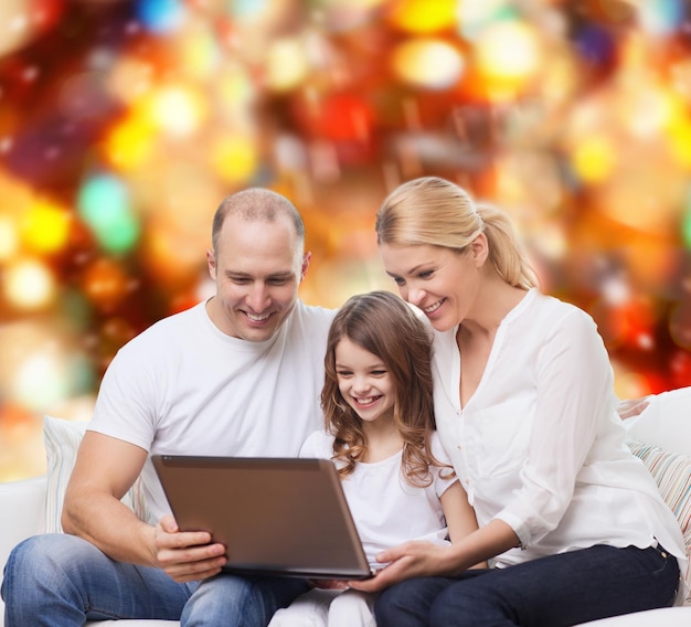 concetto di famiglia, infanzia, vacanze, tecnologia e persone - famiglia sorridente con computer portatile su sfondo a luci rosse