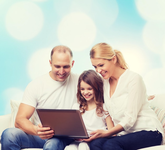 concetto di famiglia, infanzia, vacanze, tecnologia e persone - famiglia sorridente con computer portatile su sfondo di luci blu