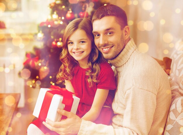 concetto di famiglia, natale, natale, felicità e persone - padre e figlia sorridenti che tengono una confezione regalo