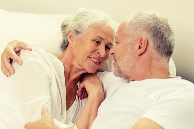 concetto di famiglia, ora di coricarsi, riposo, età e persone - accoppiatore senior felice che si trova a casa