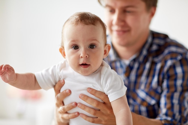 concetto di famiglia, paternità e genitorialità - primo piano di felice giovane padre sorridente con un bambino piccolo a casa