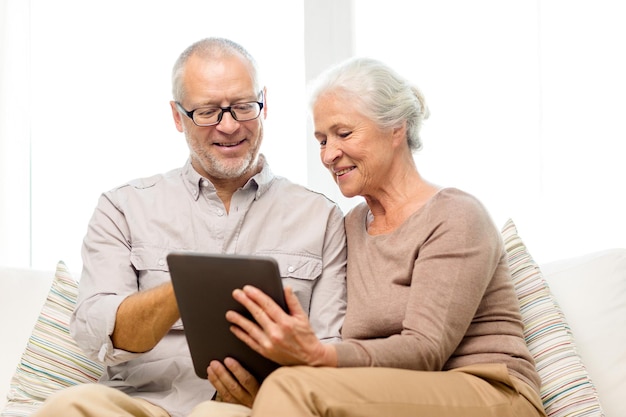 concetto di famiglia, tecnologia, età e persone - coppia senior felice con computer tablet pc a casa