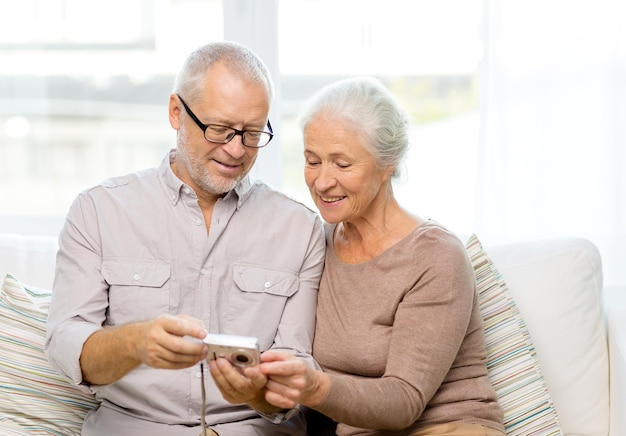 concetto di famiglia, tecnologia, età e persone - coppia senior felice con la macchina fotografica a casa