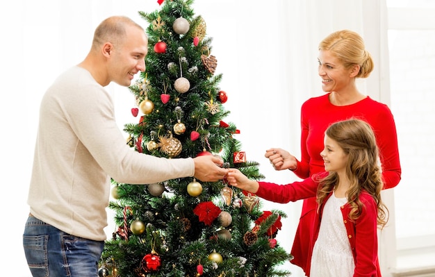 concetto di famiglia, vacanze, generazione e persone - famiglia sorridente che decora l'albero di Natale a casa