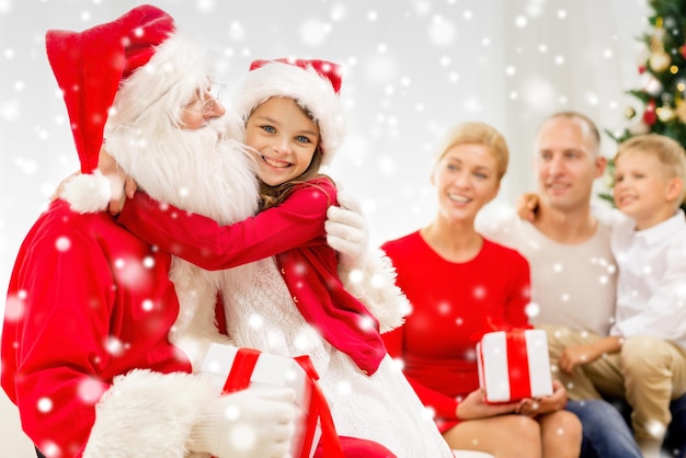 concetto di famiglia, vacanze, generazione, natale e persone - famiglia sorridente con babbo natale e scatole regalo a casa