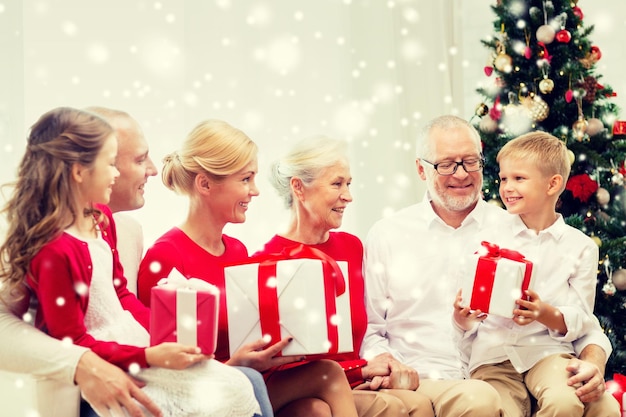 concetto di famiglia, vacanze, generazione, natale e persone - famiglia sorridente con scatole regalo seduto sul divano a casa