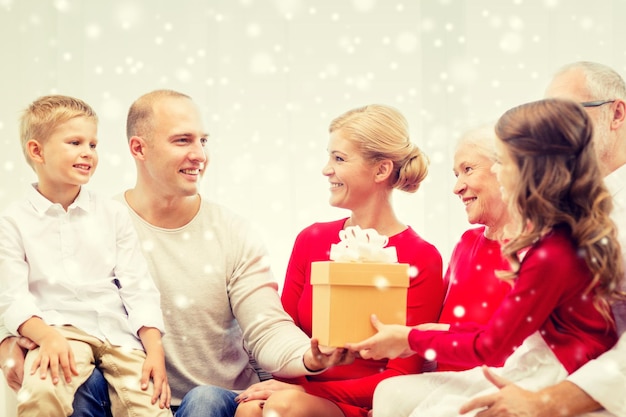 concetto di famiglia, vacanze, generazione, natale e persone - famiglia sorridente con scatole regalo seduto sul divano a casa