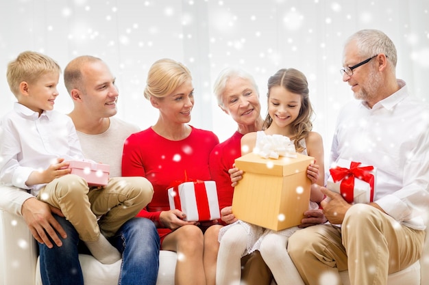 concetto di famiglia, vacanze, generazione, natale e persone - famiglia sorridente con scatole regalo seduto sul divano a casa