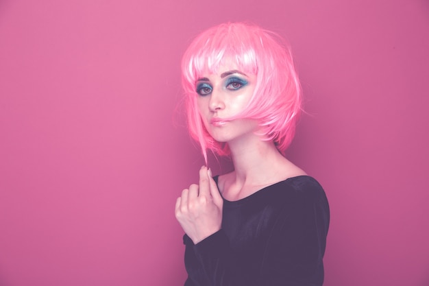 Concetto di fase retrò. Donna con i capelli rosa che tiene il porta-pellicola isolato in uno studio blu brillante.