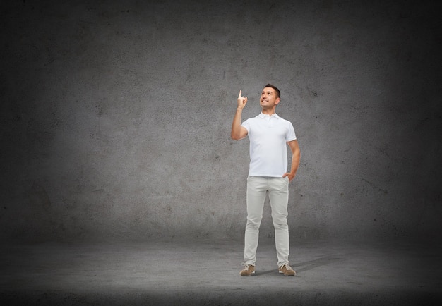 concetto di felicità, gesto e persone - uomo sorridente che punta il dito su sfondo concreto