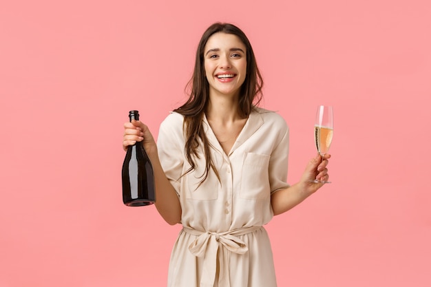 Concetto di felicità, romanticismo e amore. Sorridere splendido elegante, donna felice che celebra compleanno, giorno di San Valentino, che tiene bottiglia di champagne e vetro, godendo drink e alzare il bicchiere per l'occasione