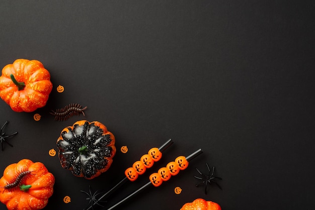 Concetto di festa di Halloween Foto vista dall'alto di piccole zucche insetti millepiedi ragni cocktail cannucce e coriandoli su sfondo nero isolato con spazio vuoto