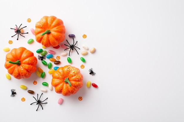 Concetto di festa di Halloween Foto vista dall'alto di piccoli ragni di zucche e caramelle su sfondo bianco isolato con copyspace