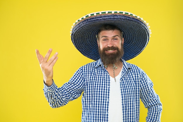 Concetto di festa messicana. Festeggia la tradizionale vacanza messicana. Divertiamoci. Ragazzo messicano felice vestito festivo pronto a festeggiare. Uomo barbuto ragazzo allegro indossare sombrero cappello messicano sfondo giallo.