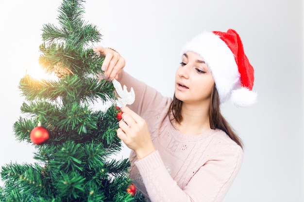 Concetto di feste - la ragazza in cappello della santa ha decorato l'albero di Natale. Aspettando Natale.