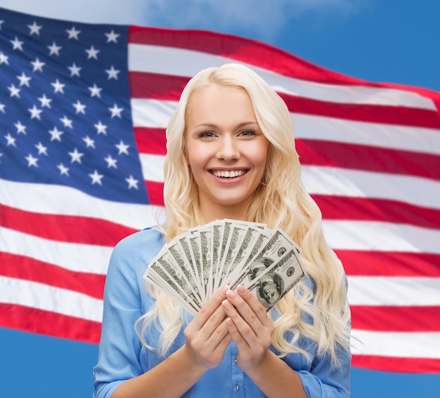 concetto di finanze e persone - donna sorridente in abito rosso con soldi in dollari americani su sfondo bandiera americana