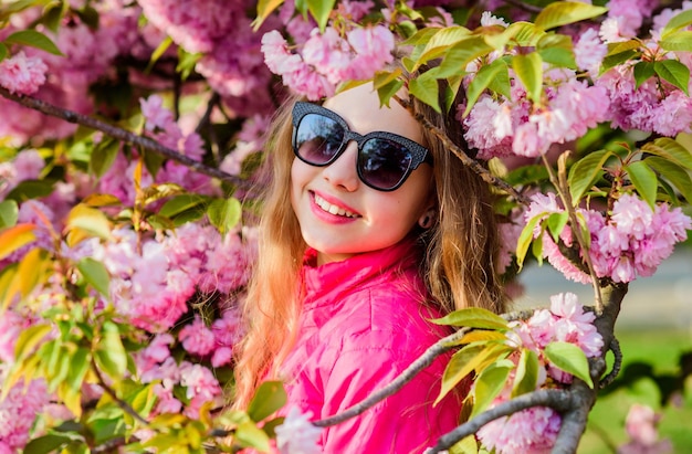 Concetto di fiore Sakura Splendido fiore e bellezza femminile Ragazza fiore di ciliegio sfondo Sakura albero in fiore Parco e giardino Piccola bambina in fiore primaverile sbocciano Goditi l'odore della tenera fioritura