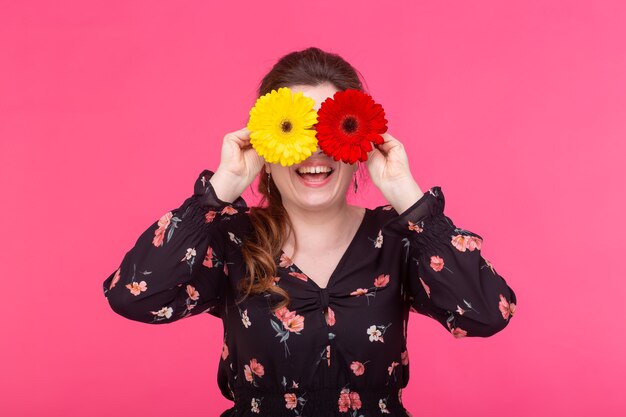 Concetto di fiori, emozioni e persone - la donna ha chiuso gli occhi con le gerbere sulla superficie rosa