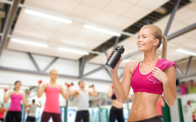 concetto di fitness, assistenza sanitaria e dieta - donna sportiva sorridente che beve acqua dalla bottiglia dello sportivo