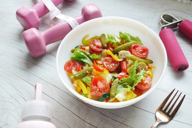 Concetto di fitness con manubri verdure fresche e nastro di misurazione su rosa