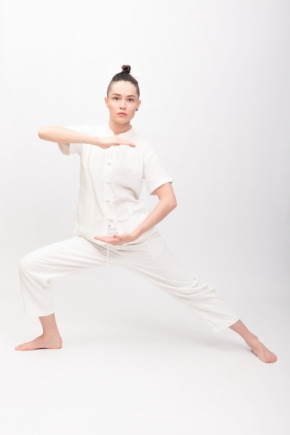 Concetto di fitness, sport, allenamento e stile di vita - Giovane donna che fa esercizio di yoga. Giovane donna che pratica tai chi chuan in palestra. L'energia di Qi di abilità di gestione cinese.