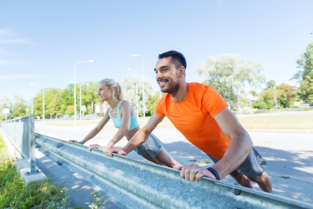 concetto di fitness, sport, allenamento e stile di vita sano - primo piano di una coppia felice che fa flessioni all'aperto