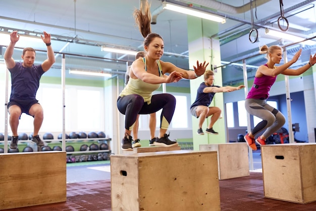 concetto di fitness, sport, allenamento ed esercizio fisico - gruppo di persone che fanno box jump in palestra