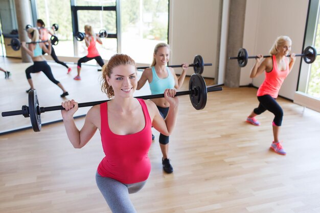 concetto di fitness, sport, allenamento, palestra e stile di vita - gruppo di donne che excercising con le barre in palestra