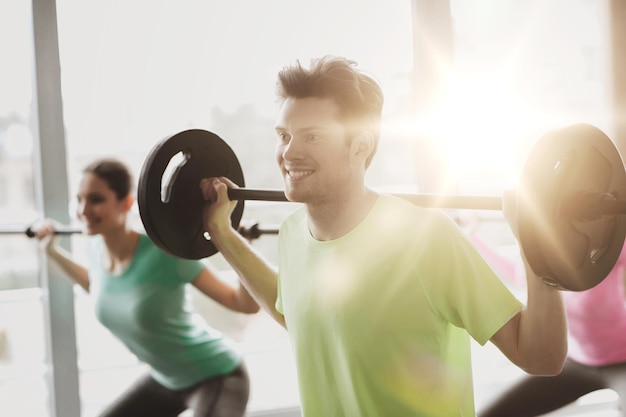 concetto di fitness, sport, allenamento, palestra e stile di vita - gruppo di persone che si esercitano con il bilanciere in palestra