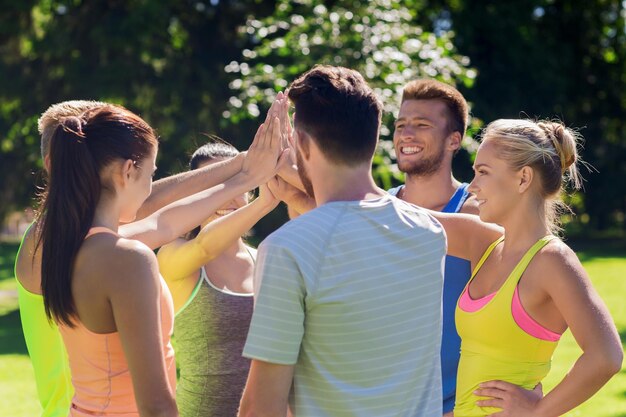 concetto di fitness, sport, amicizia e stile di vita sano - gruppo di amici adolescenti felici o sportivi che fanno il cinque all'aperto