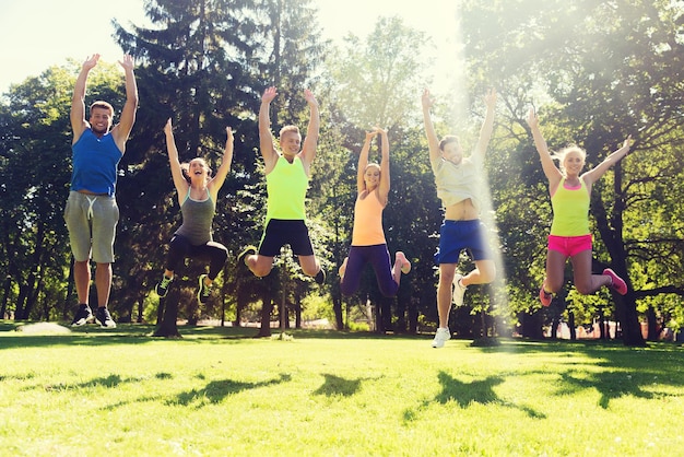 concetto di fitness, sport, amicizia e stile di vita sano - gruppo di amici adolescenti felici o sportivi che saltano in alto all'aperto