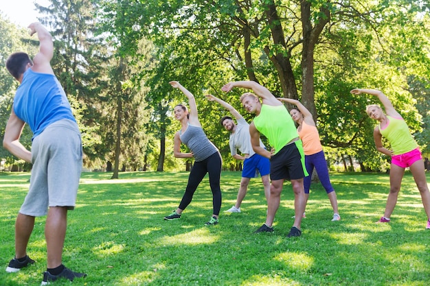 concetto di fitness, sport, amicizia e stile di vita sano - gruppo di amici adolescenti felici o sportivi che si esercitano e allungano le mani al campo di addestramento