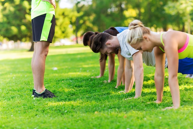 concetto di fitness, sport, amicizia e stile di vita sano - gruppo di amici adolescenti felici o sportivi che si esercitano e fanno flessioni al campo di addestramento