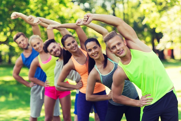 concetto di fitness, sport, amicizia e stile di vita sano - gruppo di amici adolescenti felici o sportivi che si esercitano e si allungano al campo di addestramento