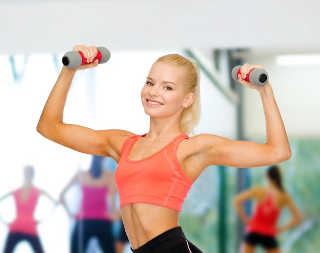 concetto di fitness, sport e dieta - sorridente bella donna sportiva con manubri