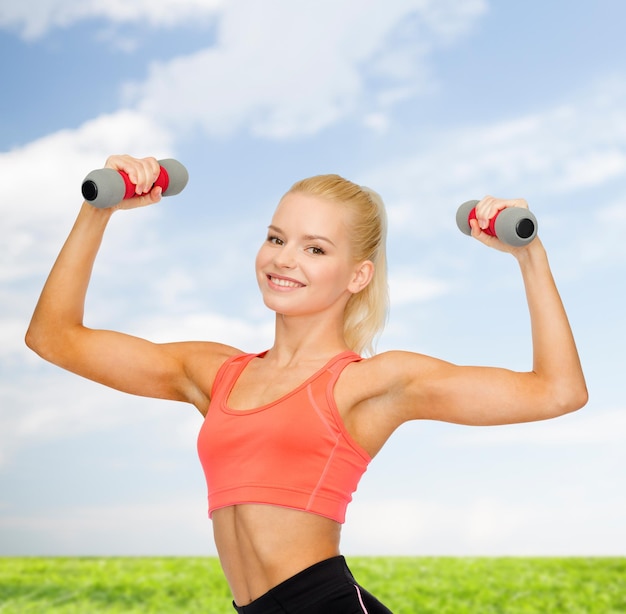 concetto di fitness, sport e dieta - sorridente bella donna sportiva con manubri