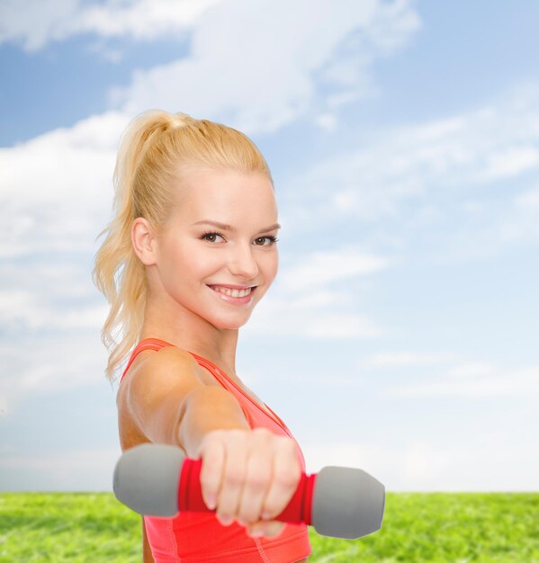 concetto di fitness, sport e dieta - sorridente bella donna sportiva con manubri