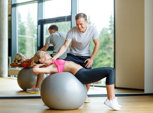 concetto di fitness, sport, esercizio e dieta - giovane donna sorridente e personal trainer in palestra