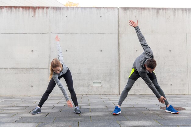 concetto di fitness, sport, esercizio fisico, formazione e persone - primo piano di coppia che si estende sulla strada della città